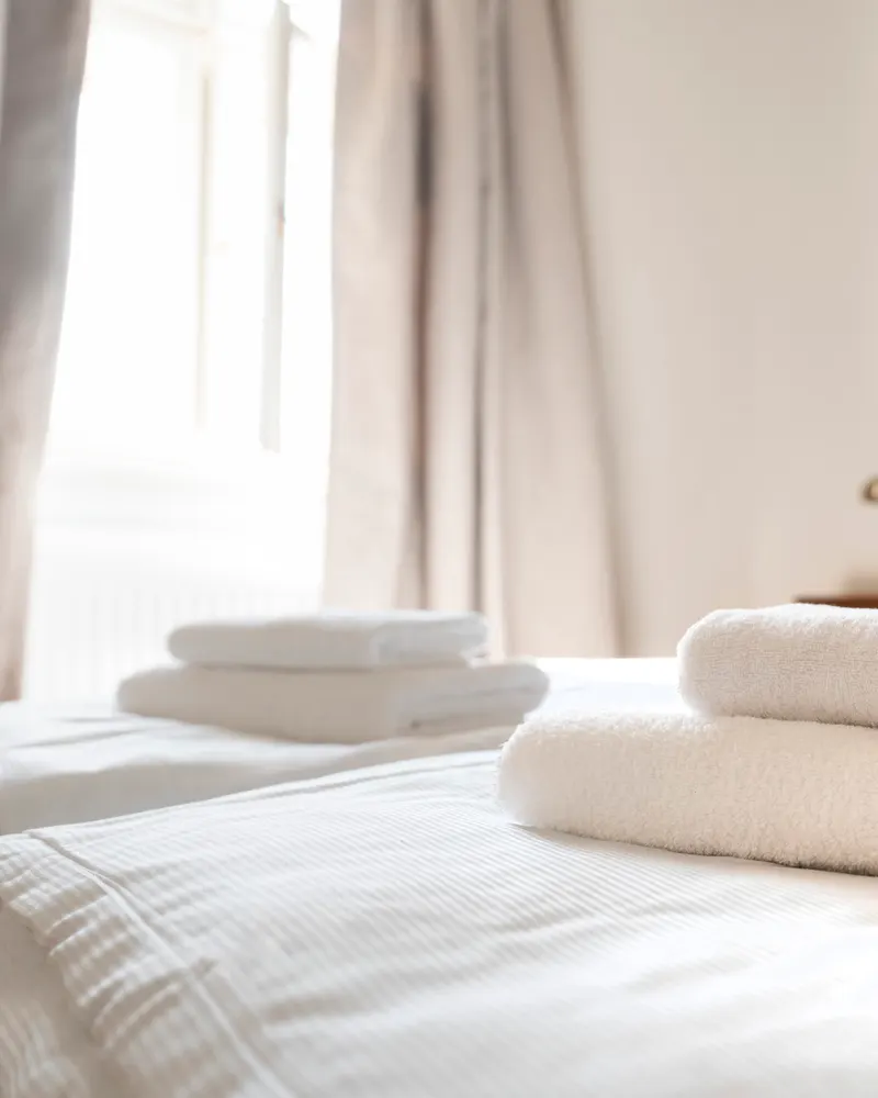 Złożone ręczniki na zasłanym łóżku w apartamencie